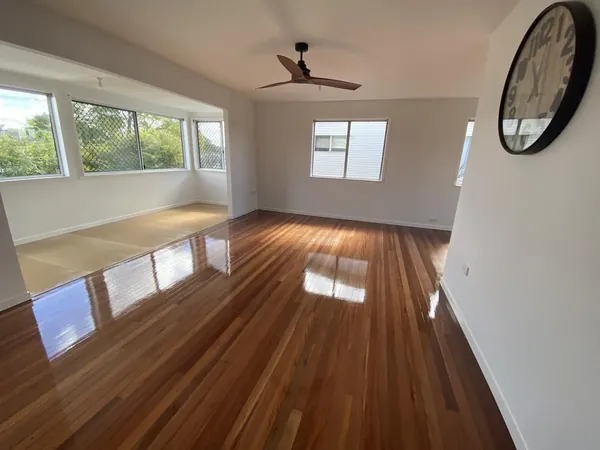 Glossy timber floor in a bright living room with a ceiling fan and wide windows
