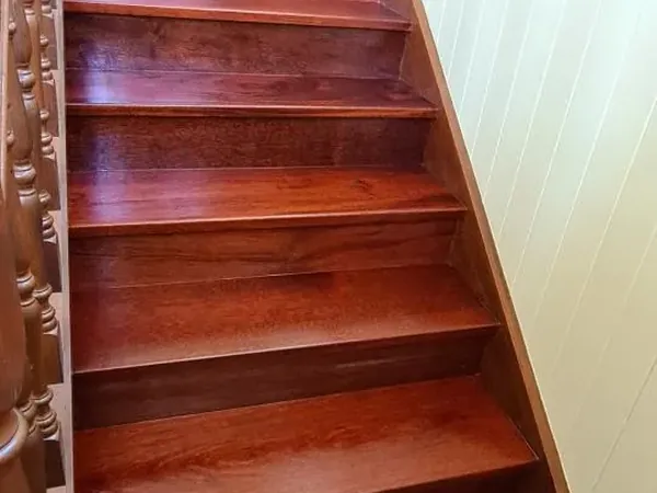 Polished reddish timber staircase with a matching timber balustrade