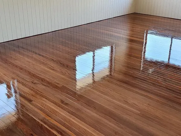 Reflective brown timber floor beside white skirting boards and panelled walls