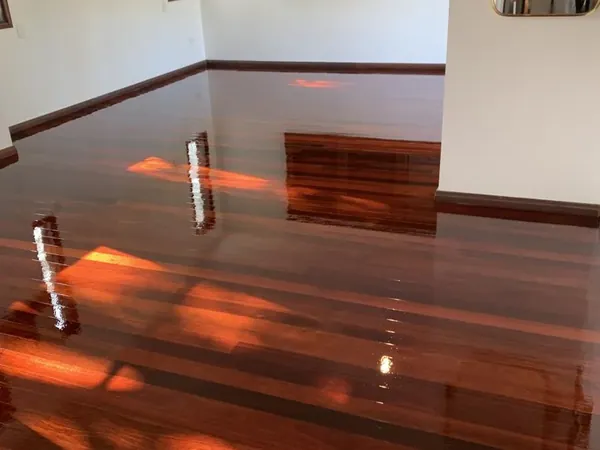 Sunlit polished floorboards in a living room with white walls