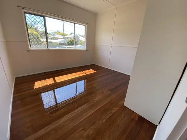 Polished brown floorboards in a bedroom with a wide window