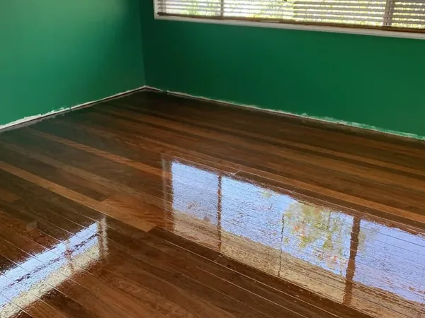 Glossy timber floor in a bedroom with green walls and a large window