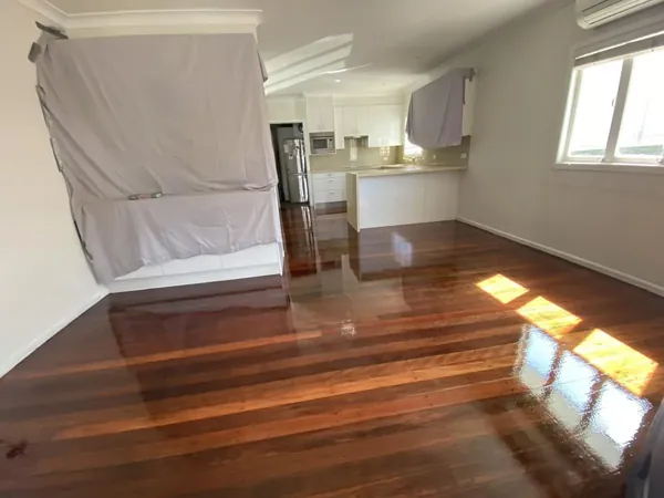 Sunlight across a newly finished timber floor beside a white kitchen