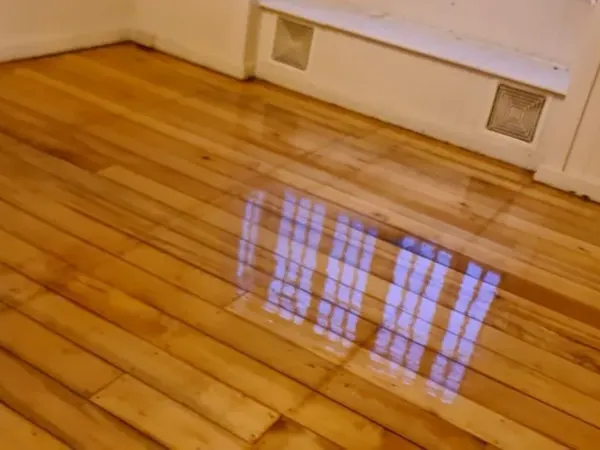 Golden floorboards with a glossy finish beneath a curtained window