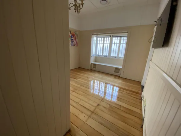 Light polished timber floor in a room with white panelled walls and a window blind