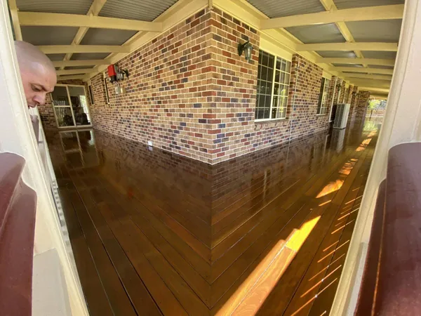 Finished timber veranda wrapping around the corner of a brick house