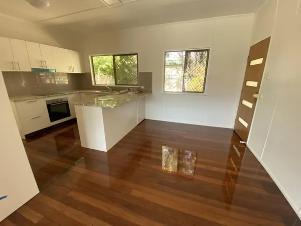Polished timber flooring around a white kitchen island and dining space