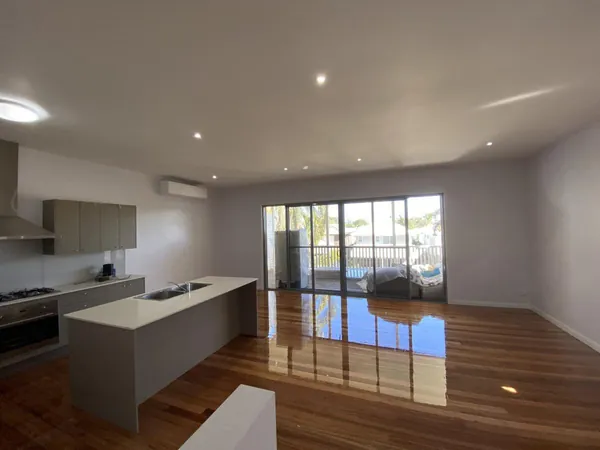 Polished brown timber floor through a modern open-plan kitchen and living area