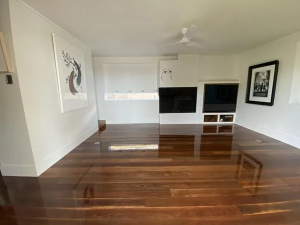 Polished timber living room floor with white built-in shelves and window blinds