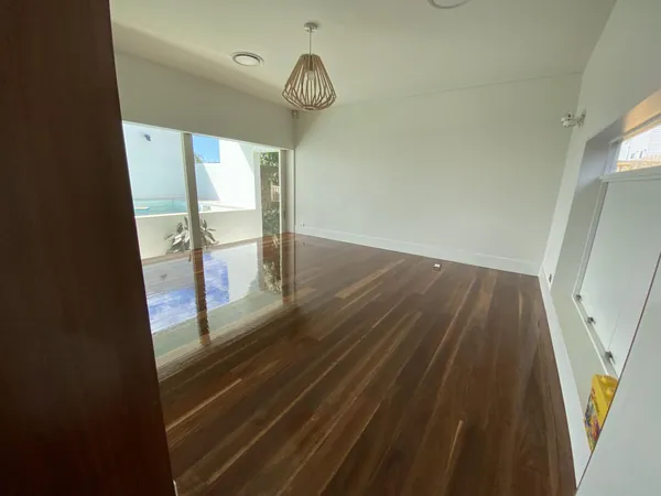 Dark glossy floorboards in a bright room with sliding glass doors