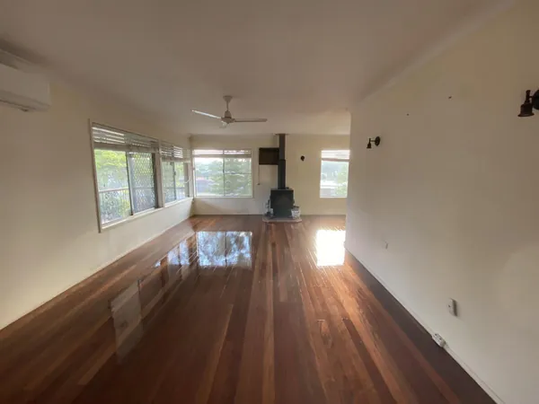 Polished reddish timber floor stretching through a long empty living room