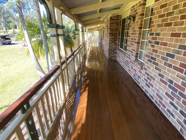 Long covered timber veranda beside a brick wall and timber railing