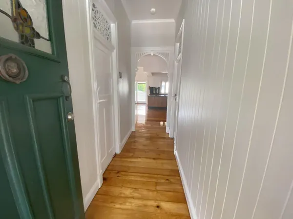 Golden floorboards running through a hallway with white panelled walls