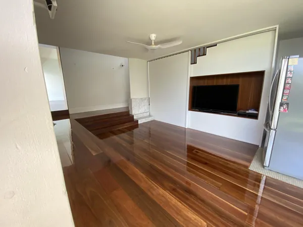 Glossy timber floor in a white living room with built-in wall shelving