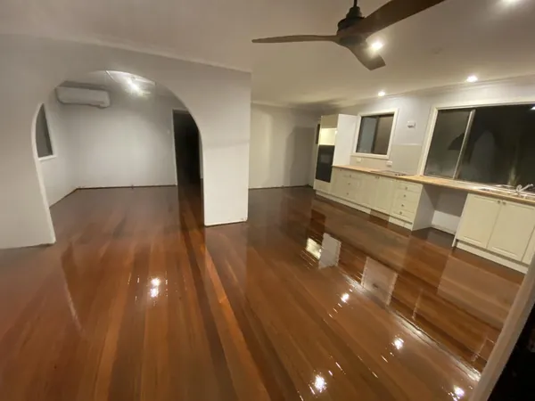 Polished timber floor beneath a white kitchen and adjoining dining space