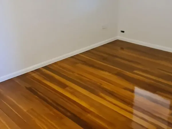 Warm brown floorboards in an empty bedroom with white skirting boards
