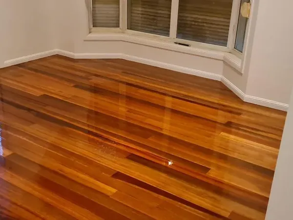 Richly coloured polished floorboards beneath a bay window
