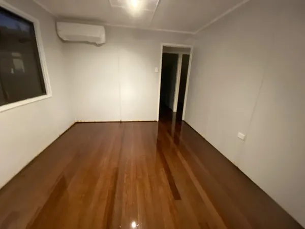 Polished brown bedroom floor beneath a wall-mounted air conditioner