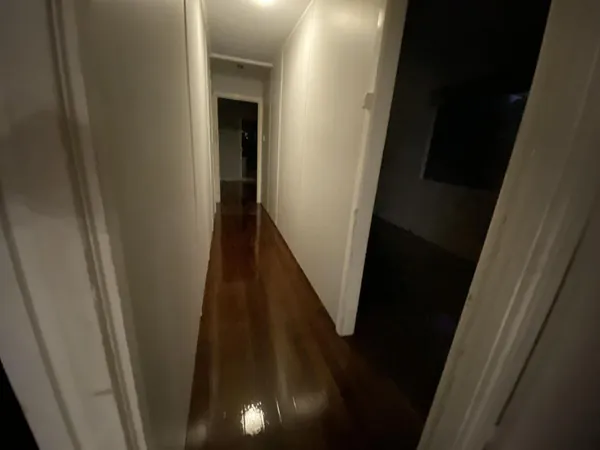 Dark glossy floorboards in a narrow hallway beside an open doorway