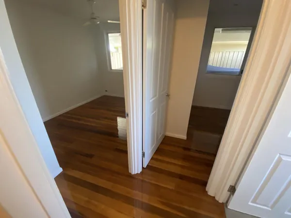 Polished timber flooring connecting adjoining rooms through white doorways