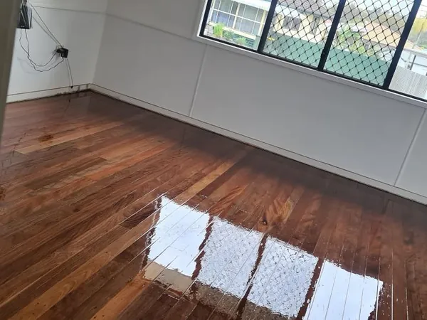 Glossy brown bedroom floor beneath a wide screened window
