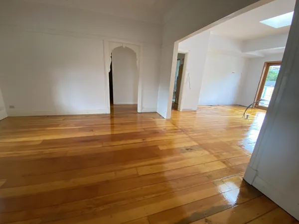Golden polished timber flooring through connected rooms with an arched doorway