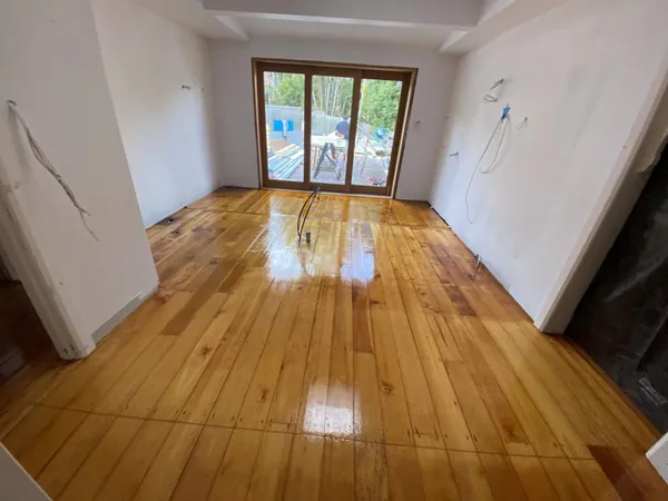 Glossy golden floorboards in an empty room with timber-framed glass doors