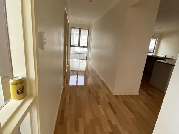 Light timber flooring connecting an entry hallway and kitchen