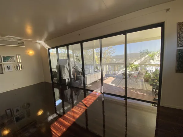 Dark polished floorboards beside sliding glass doors overlooking a balcony