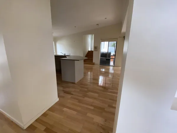 Timber flooring connecting a white kitchen with an adjoining living space