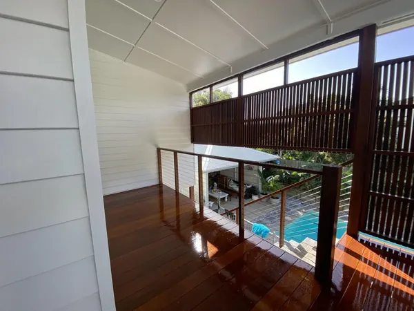 Covered timber deck overlooking a pool through a timber privacy screen