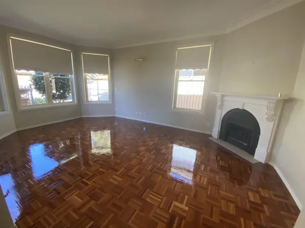 Glossy parquet floor in a living room with a fireplace and bay windows