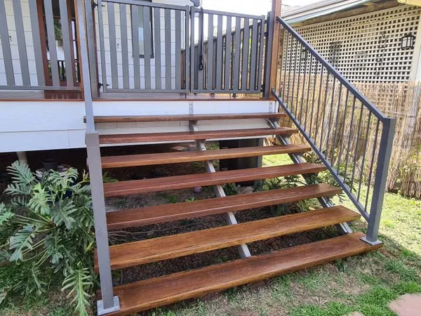 Finished outdoor timber steps leading from a raised deck to the lawn