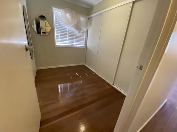 Brown finished timber floor in a small room with a window blind