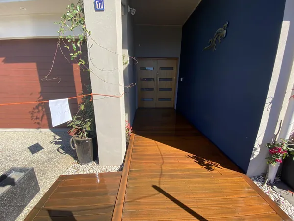 Finished timber entry deck beside a blue wall and exterior doorway
