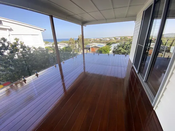 Glossy timber balcony floor beneath a covered roof overlooking surrounding homes