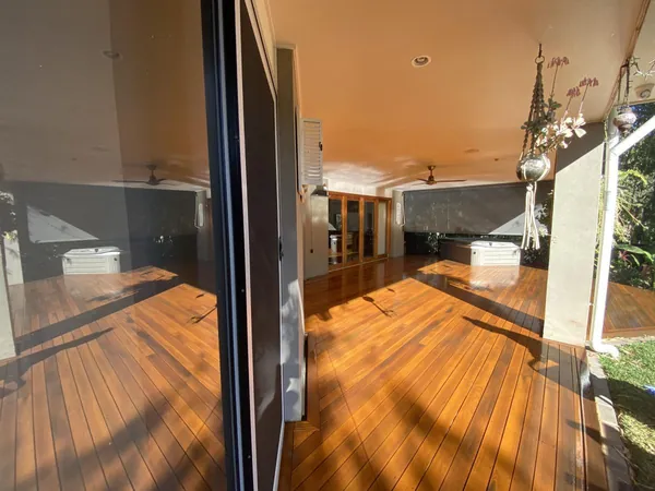 Sunlit glossy timber floor beside sliding glass doors and a kitchen
