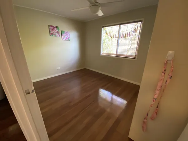 Glossy brown floorboards in an empty bedroom with a ceiling fan