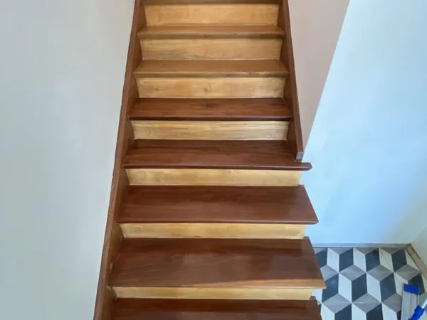 Straight timber staircase with white walls and a glossy finish