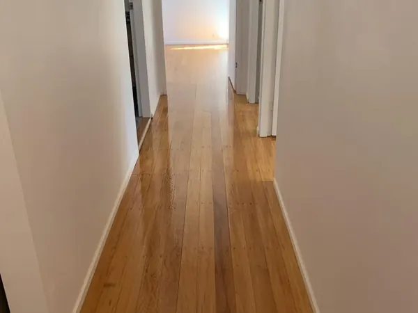 Light timber floor running through a long narrow hallway with white walls