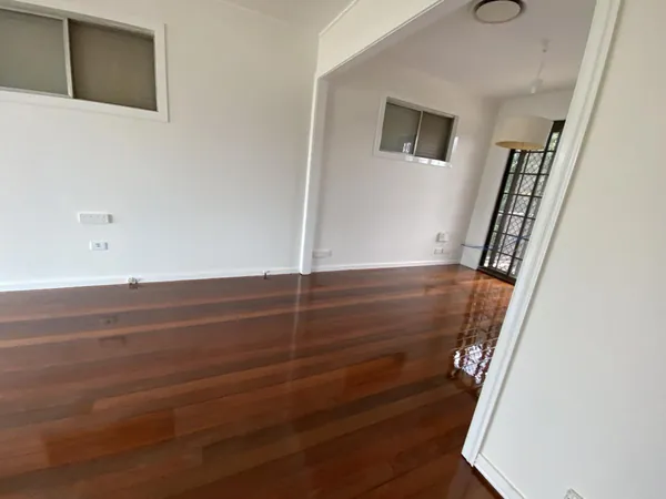 Dark polished timber floor viewed through an open white doorway