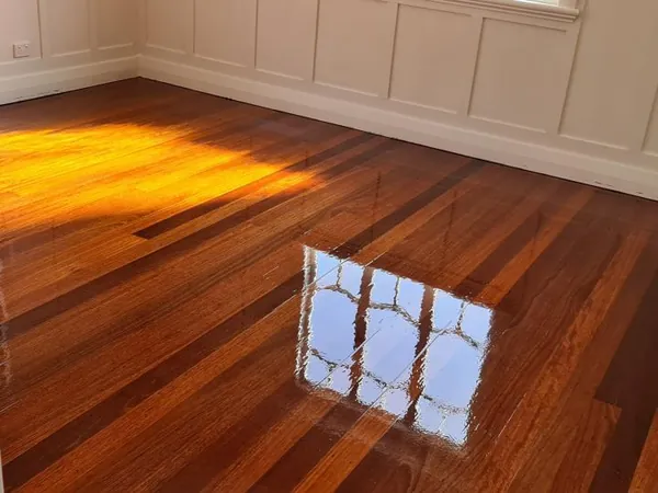 Sunlight across richly coloured timber floorboards beneath a window