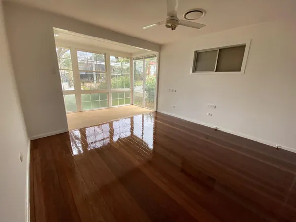 Reflective reddish timber floor in a living room with wide windows
