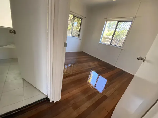 Glossy timber bedroom floor viewed from an adjoining tiled room