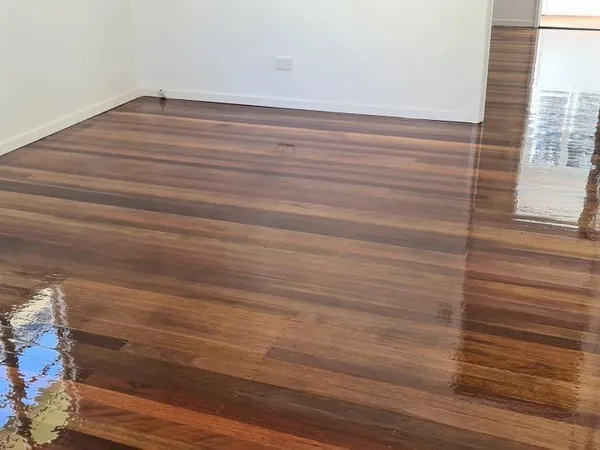 Polished dark timber floor in an empty room beside an open white door