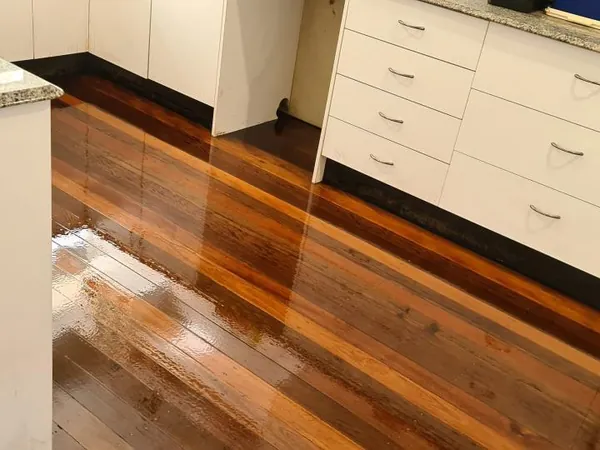 Reflective striped timber floor beneath white kitchen cabinets