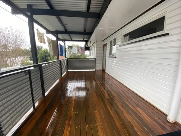 Long covered timber deck with a glossy finish and horizontal metal railing