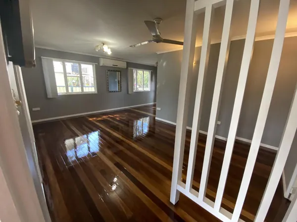 Glossy living room floor viewed past a white stair balustrade