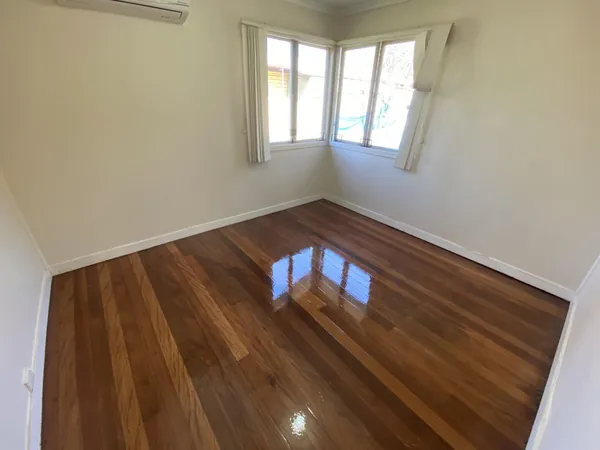 Polished brown bedroom floor beneath a window with curtains